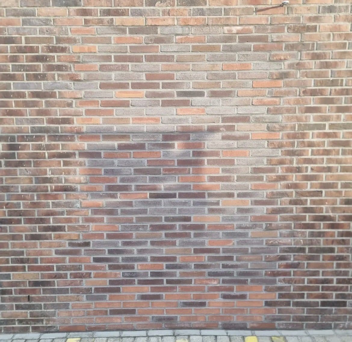 Herstelde plek in het metselwerk elders op dezelfde gevel, met een lichte kleurafwijking ten opzichte van de omliggende steen